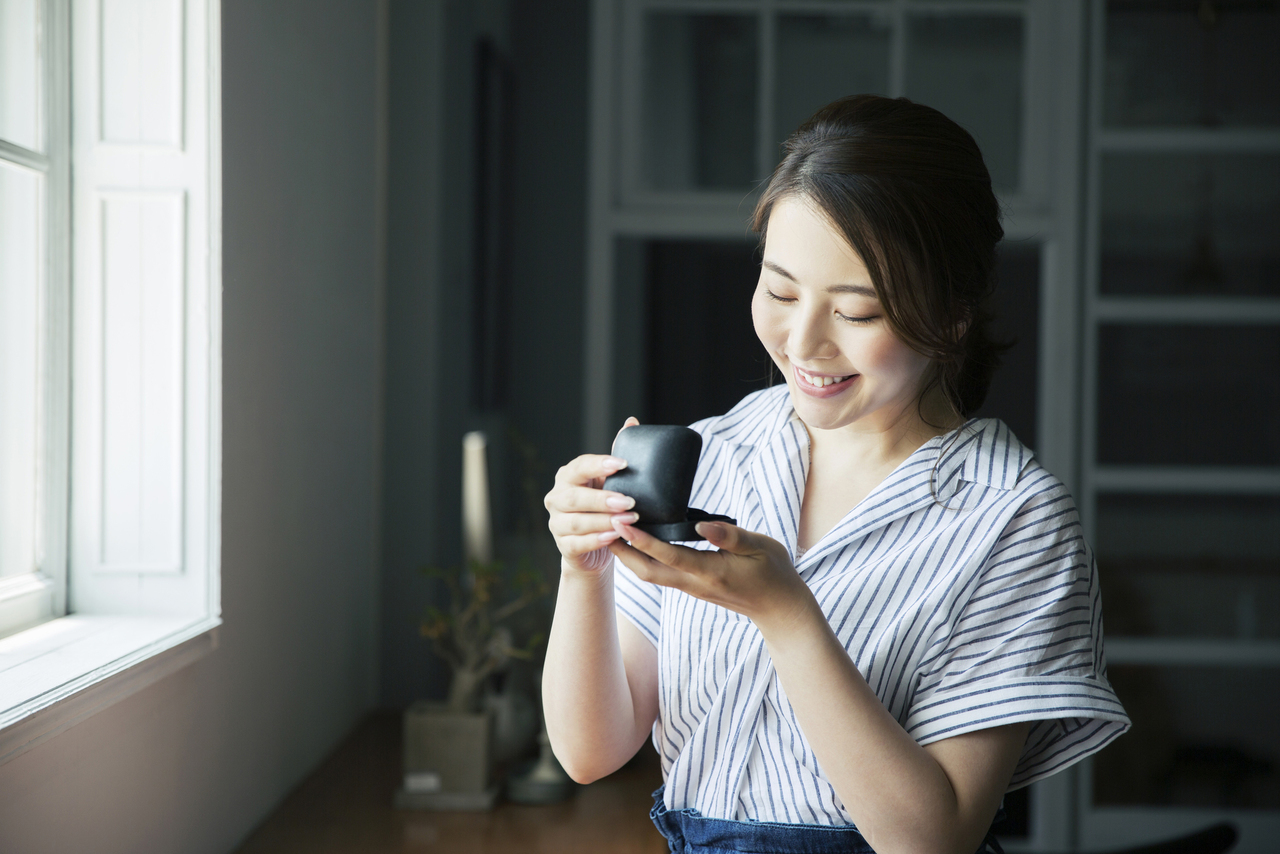 窓際で指輪をみつめ笑顔の20代女性
